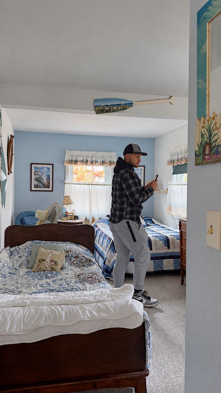 Greg Valentgas taking notes on his phone in a blue bedroom during a walkthrough