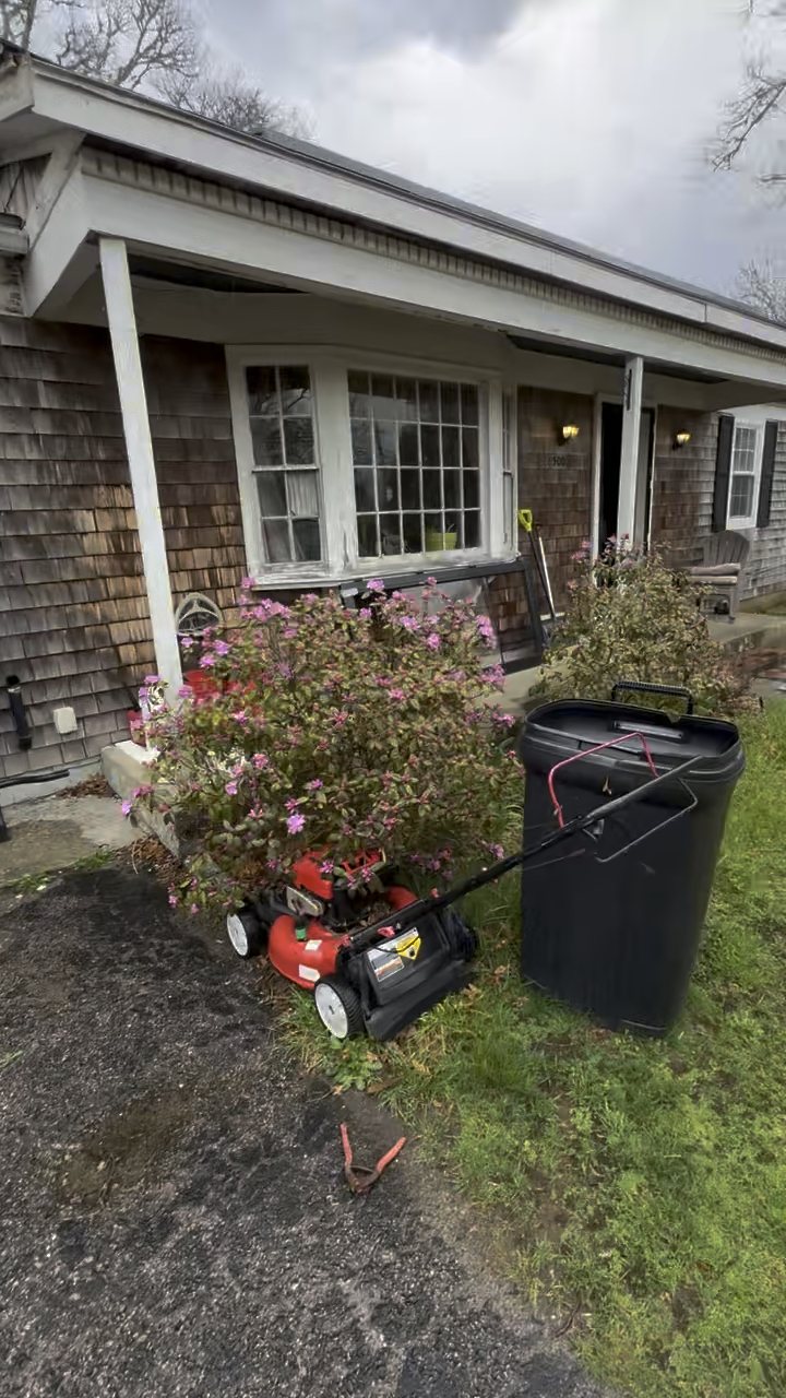 Front of a cedar-shingled ranch in Harwich with a covered porch, bay window and flowering shrubs