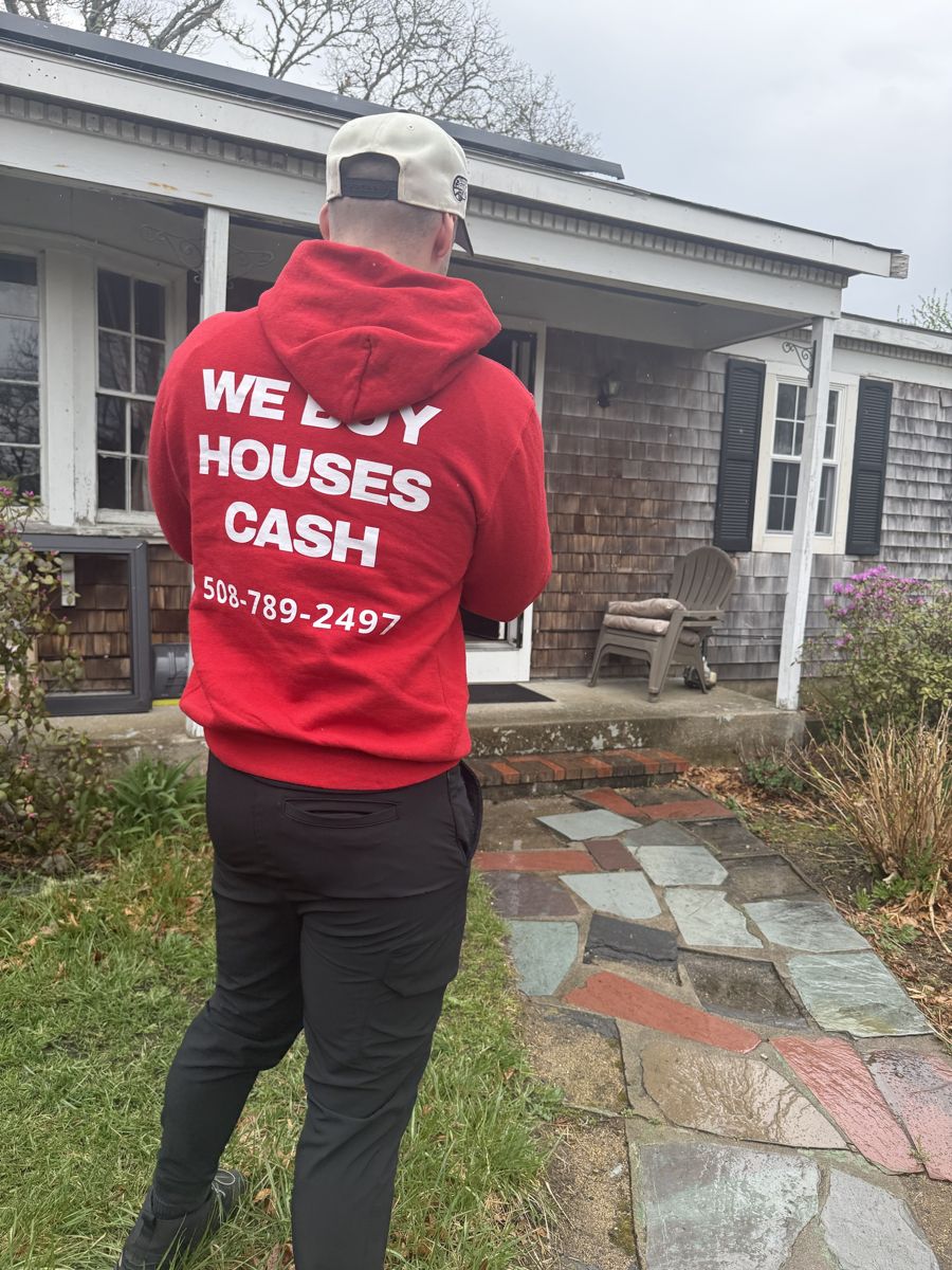 Greg Valentgas in a red We Buy Houses Cash hoodie at the front walk of the Harwich home