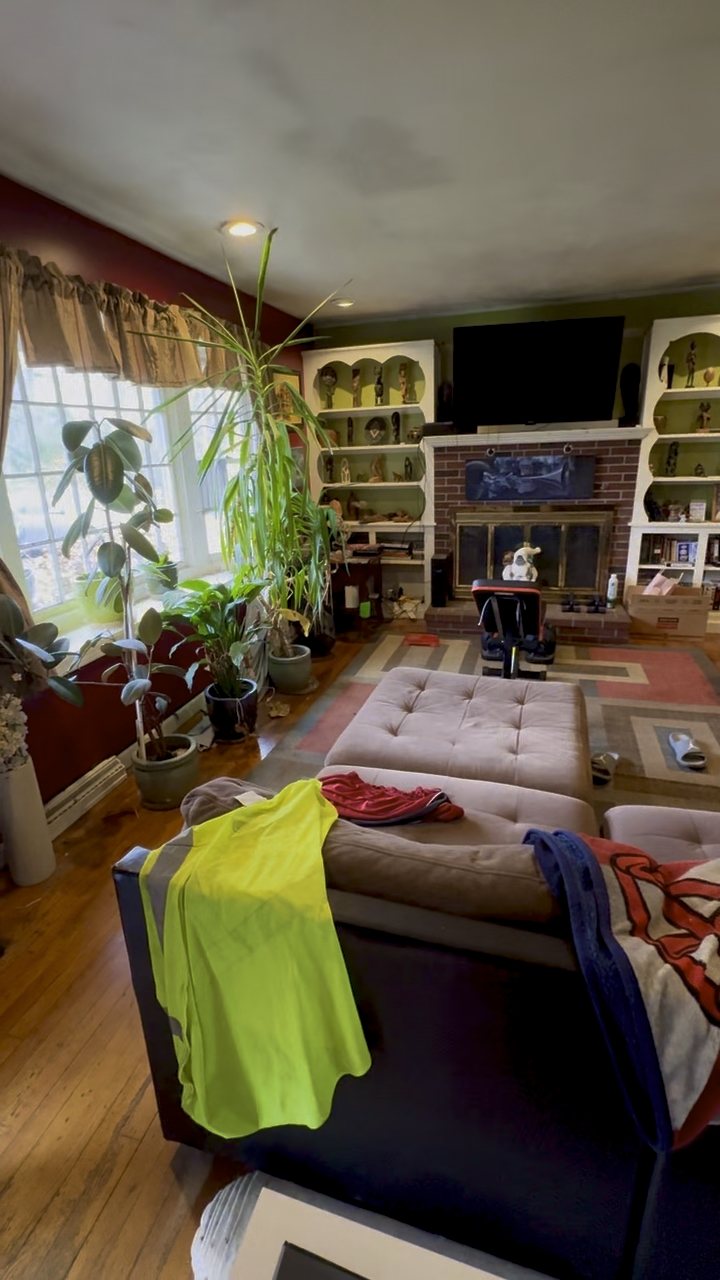 Living room with a brick fireplace, built-in shelving and hardwood floors