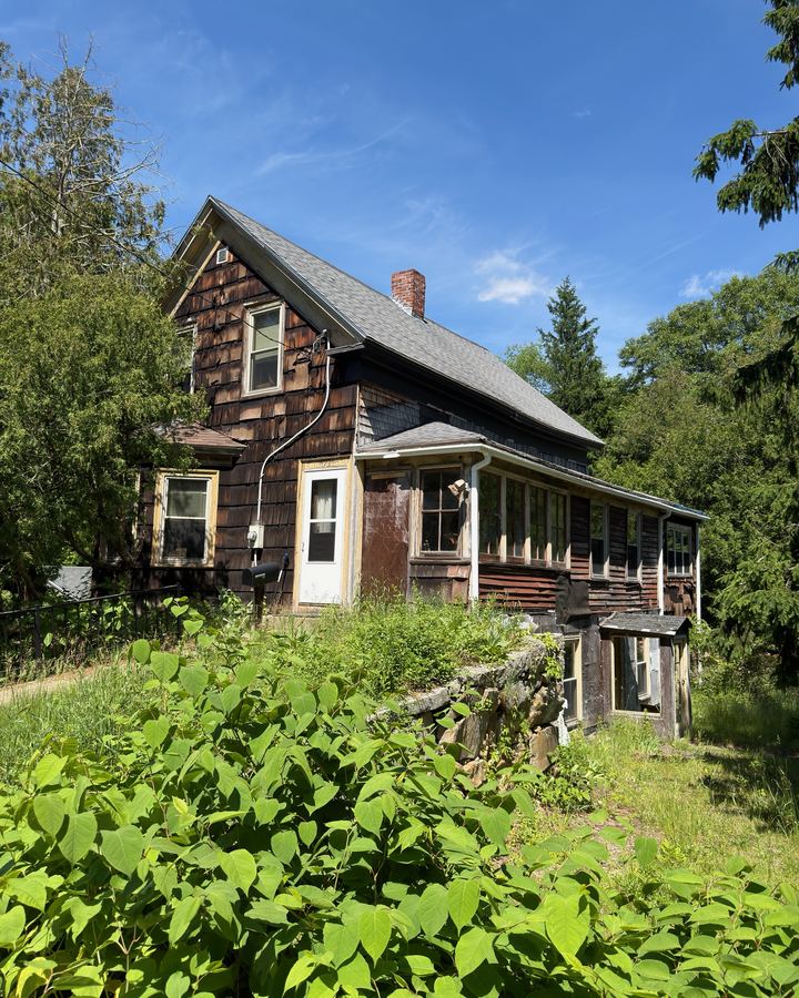 Older Milford, MA house with worn shingle siding and an overgrown yard, from our August 2026 closing